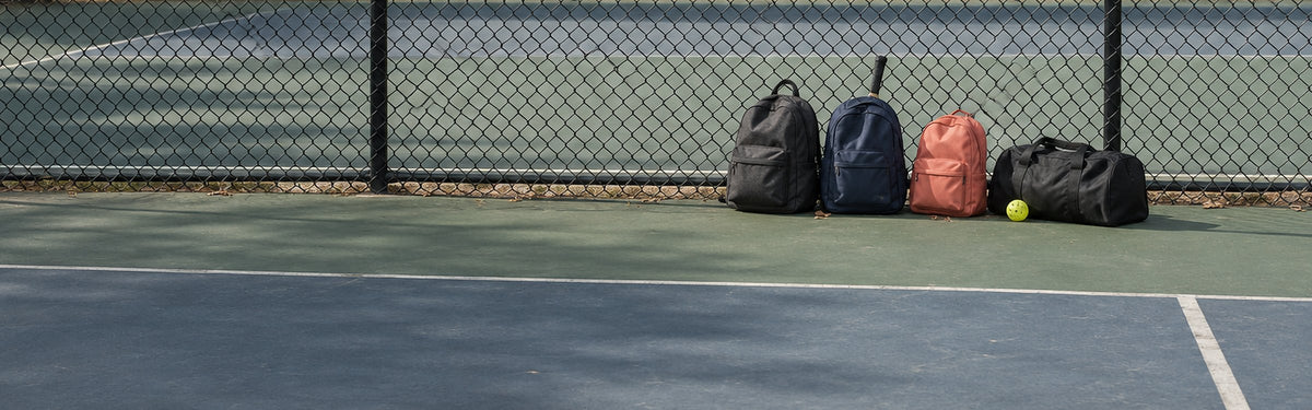 Sports backpacks lined up against a court fence