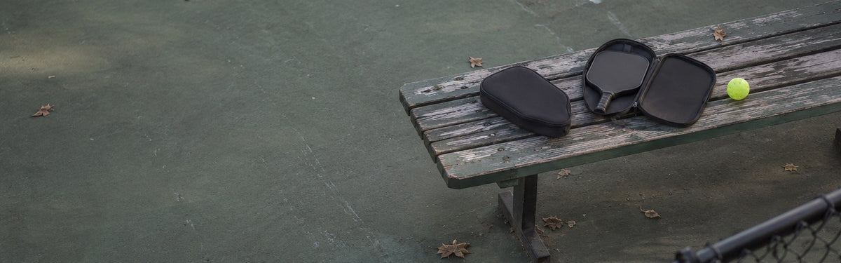 Padded paddle cases on a courtside bench