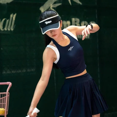 Player in navy kit hitting a low ball beside a ball cart